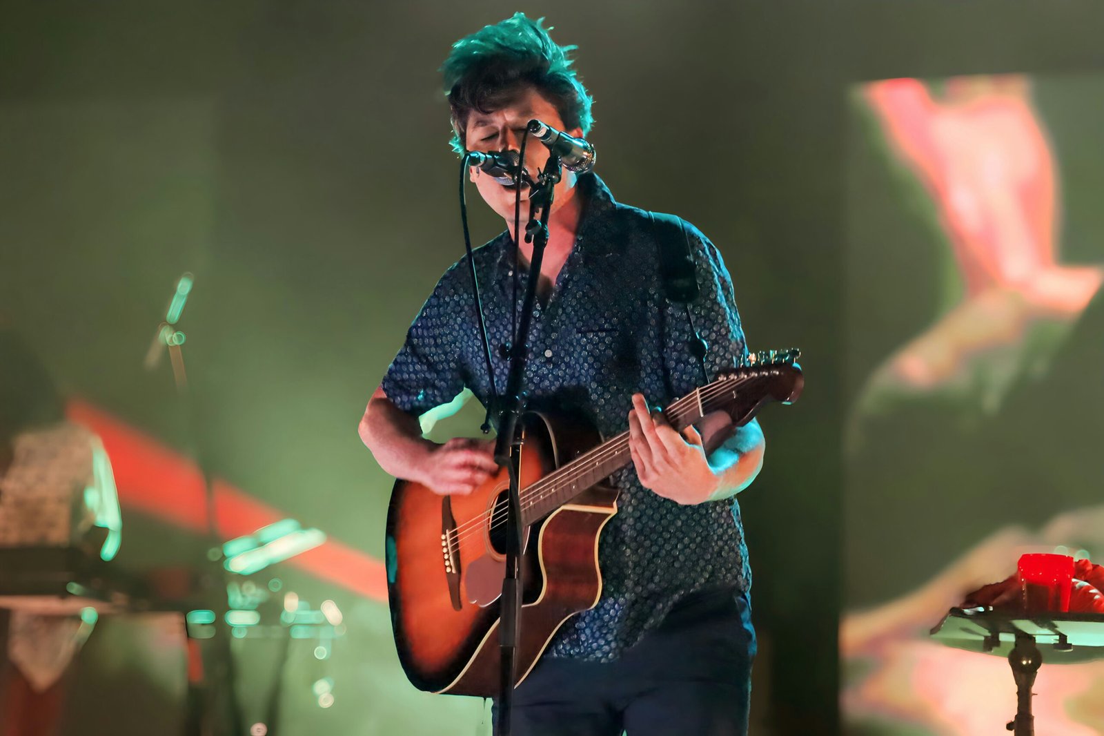 a man playing a guitar while singing into a microphone